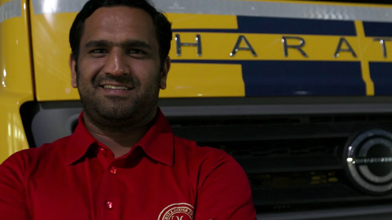 A driver in a red shirt in front of his truck