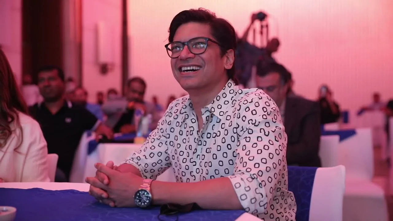A guest smiling at his table, pink light